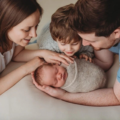 A joyful moment of a mother, father, and their son embracing their newborn baby with love