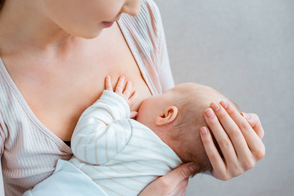 During the early days of breastfeeding, a mother lovingly cradles her baby's head as she breastfeeds