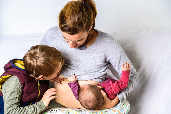 Mother breastfeeding 2 kids in tandem