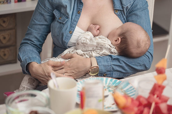 A mum breastfeeding and having lunch