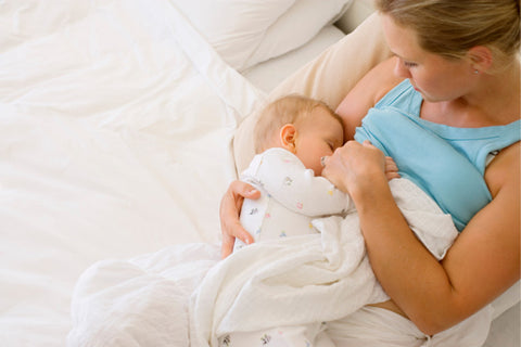 a mother breastfeeding baby in bed 