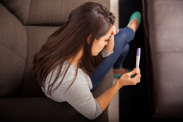 Woman is looking at a pregnancy test worryingly