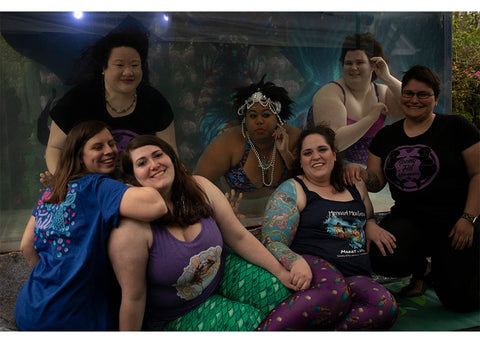 Photo by Asterism. 3 fat mermaids in tank. four friends in front.