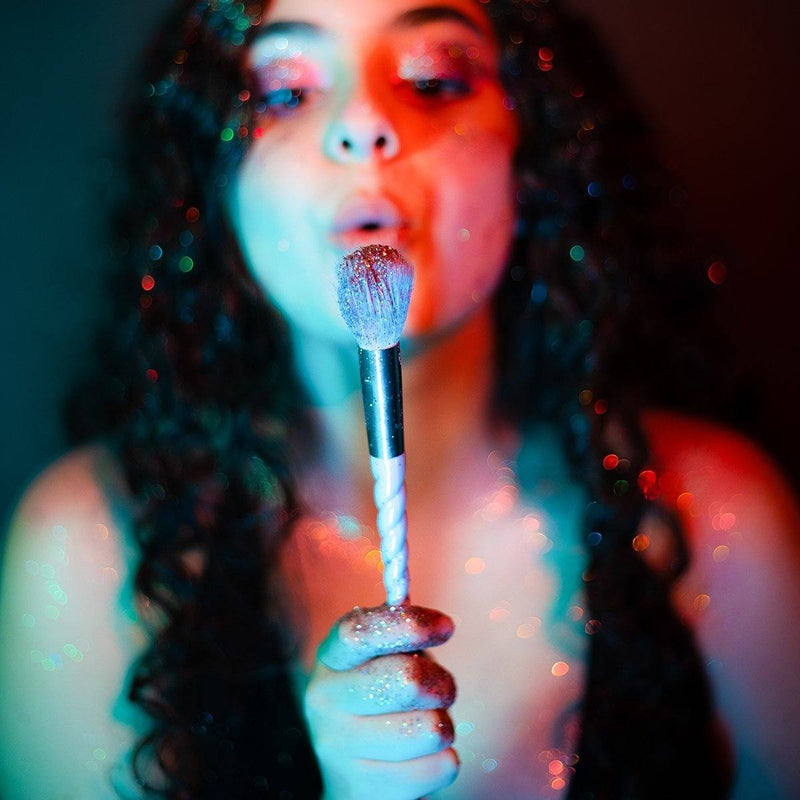 Girl blowing eco friendly biodegradable ultra sparkle glitter sparkles from a make up brush