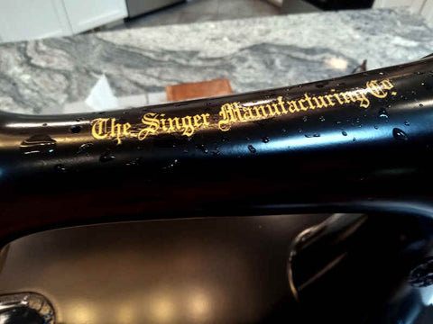 Singer 66 sewing machine from top, 'The Singer Manufacturing Co.' in gold gothic script applied to the black glossy enamel and still wet