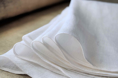 Closeup shot of a stack of crisp white linen handkerchiefs, folded.