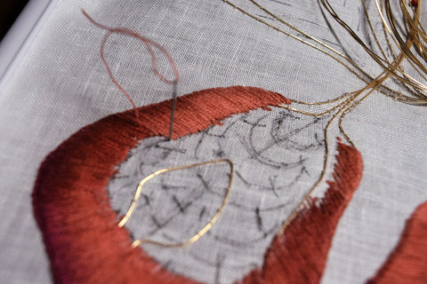 Closeup of embroidered iris petal showing shading from russet to dark peach