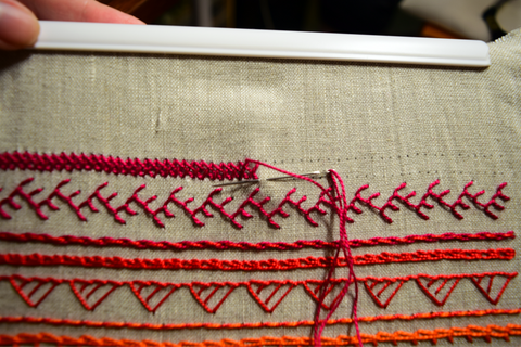 Hand embroidery band sampler in progress showing closed herringbone stitch in red thread