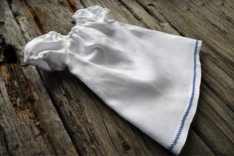 Baby peasant dress of white linen with gathered sleeves and blue feather stitch at hem 