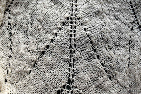 Closeup of white knitted shawl showing leaf veins and handspun texture
