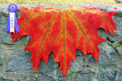 Handspun maple leaf shawl draped over stone wall with Best of Dept. ribbon