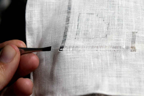 Pulling individual threads out of the fabric to create the drawnwork motifs