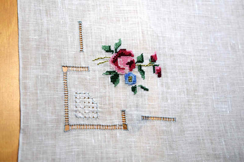 Completed replica handkerchief; cross stitched rose and forget-me-not over open and lacy drawnwork motifs in one corner