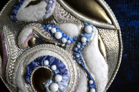 Rabbit in blue and silver embroidery heavily padded in a silver circle on blue ground