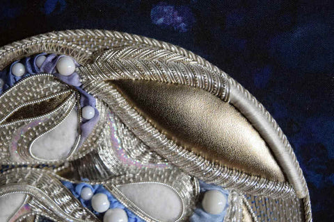 Closeup of silver rabbit partially worked in goldwork embroidery; the top of the ear is in progress and the face nearly finished.