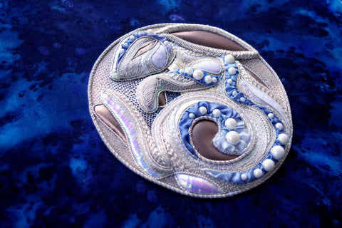 Silver rabbit worked in a circle like the Moon, viewed at an angle so the height of the embroidery can be seen