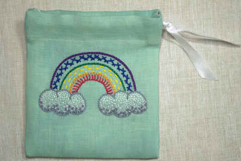 Finished drawstring pouch with embroidered rainbow worked in a variety of stitches on green linen pouch with drawstring closure