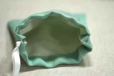 Finished drawstring pouch open showing green outer and cream inner fabric with ribbon closure