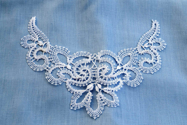 Bobbin lace necklace in Vologda style set on a background of pale blue linen