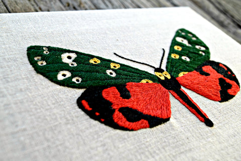 Red and green butterfly embroidered on linen