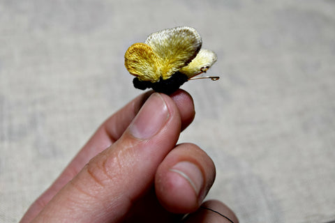 Tiny yellow stumpwork embroidered butterfly in hand