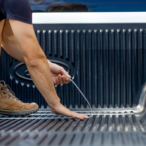 Man applies CatTongue anti-slip grip tape to truck bed. 