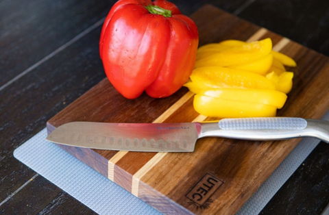 Knife with grip tape sits on cutting board in the kitchen.