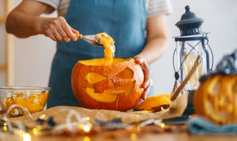 Man scoops out pumpkin guts from jack-’o-lantern. 