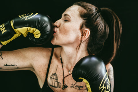 woman kissing black and yellow boxing glove 