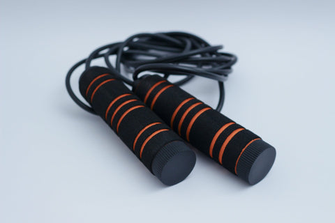 black jump rope with orange stripes on floor 