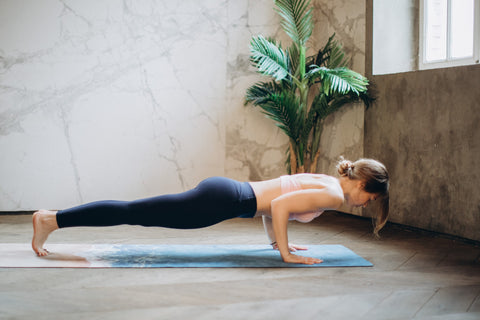 woman in black leggings doing plank exercise on yoga mat 