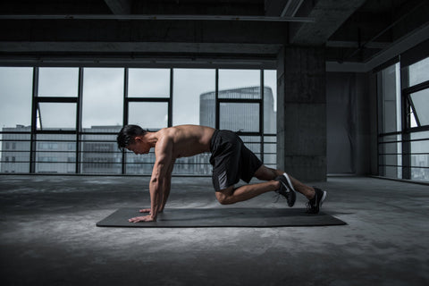 shirtless man working out on a black gym mat 