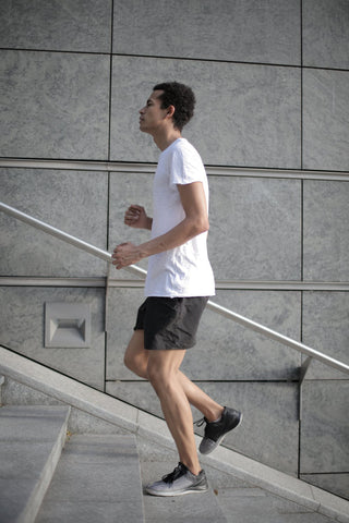 a man in a white t-shirt doing cardio on concrete steps