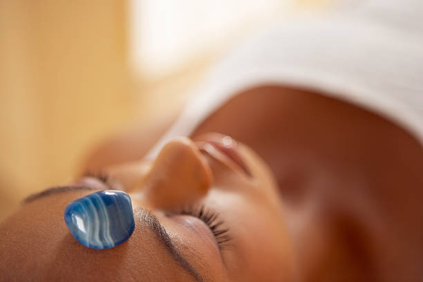 woman laying down receiving crystal healing treatment with blue agate on forehead