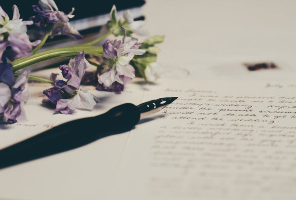 Fountain pen on letter with flowers sitting on paper.