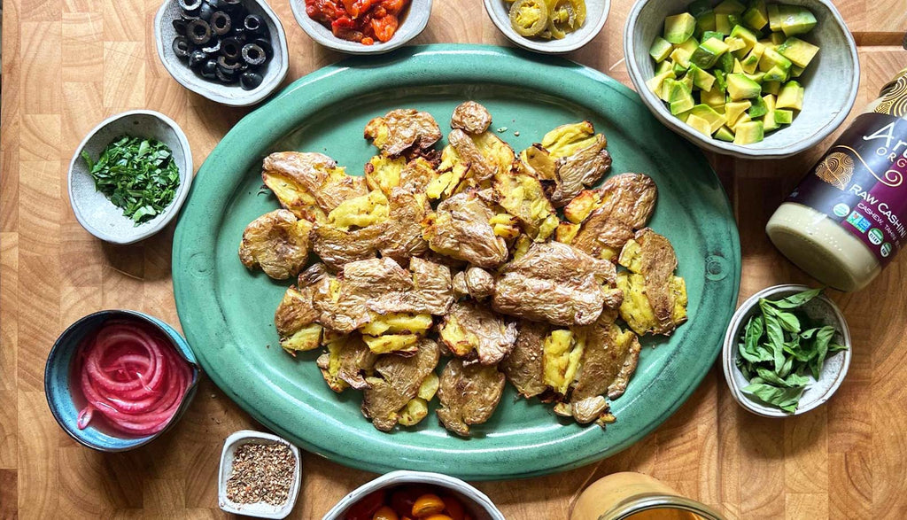 Smashed potatoes on a plate surrounded by ingredients prepped and ready in small bowls.