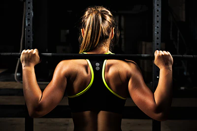 woman back lifting bar setting goals for fitness