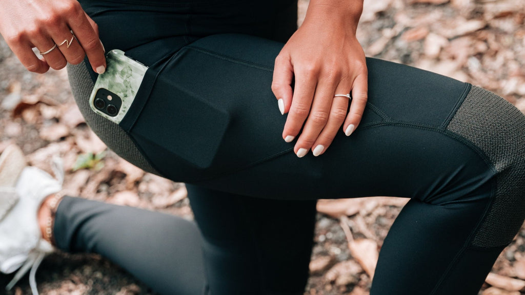 White woman wearing a Black Hiking Tights from BARA Sportswear. The picture shows a close up of the Hiking Tights' pockets.