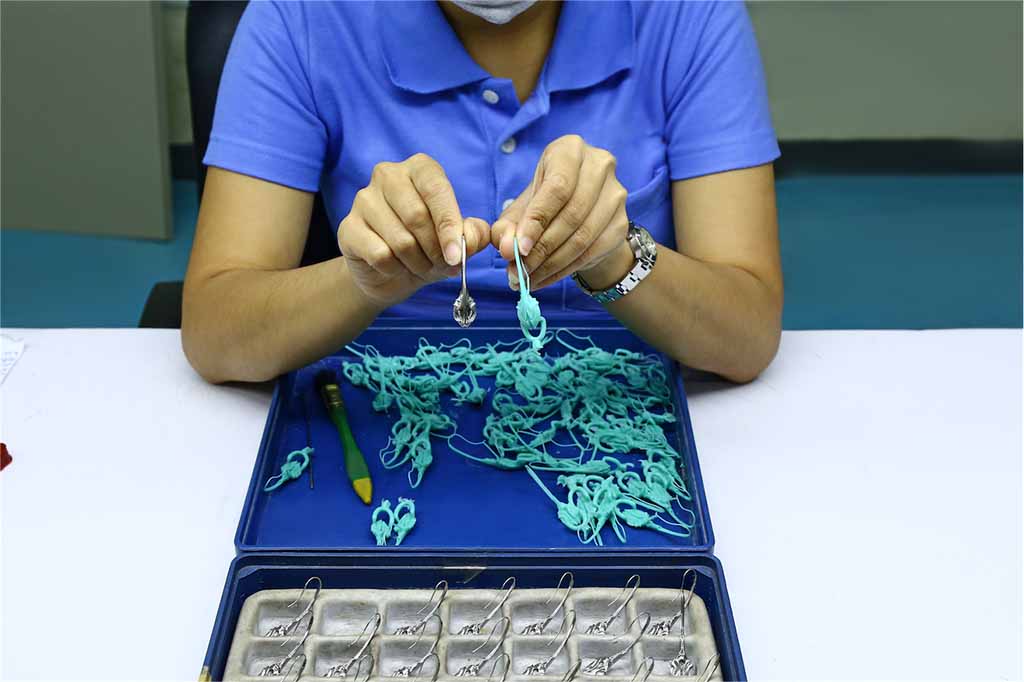 ethical jewelry production. Worker holding the wax molds which will be cast using lost wax process next to the finished part