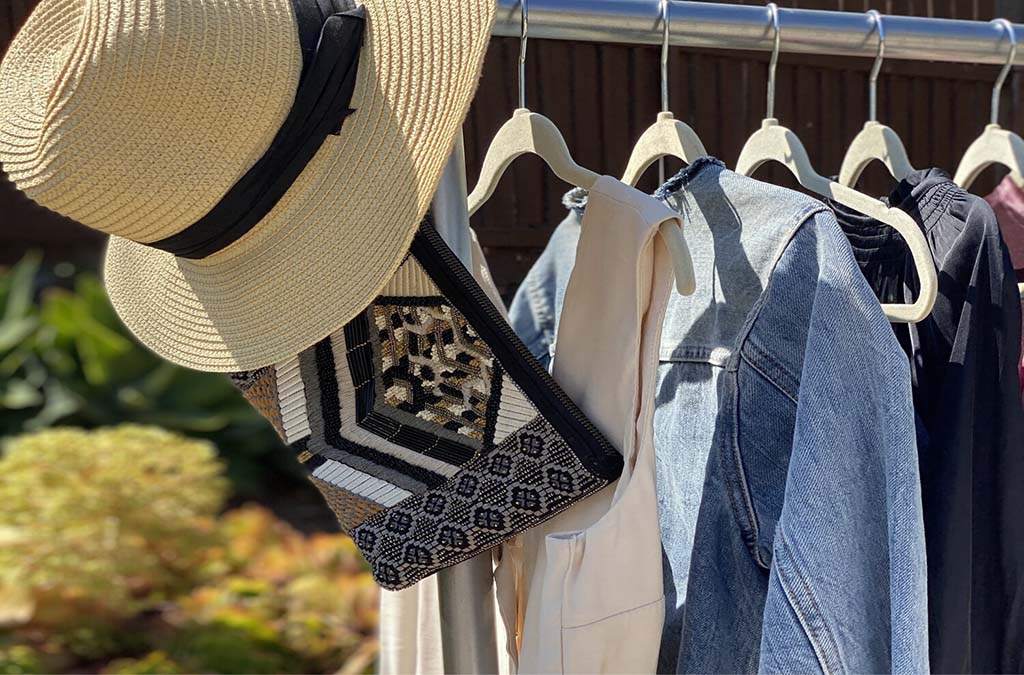 How to build more sustainable habits. Image of clothing rack with casual clothing neatly hung and a hat hanging at the end. 