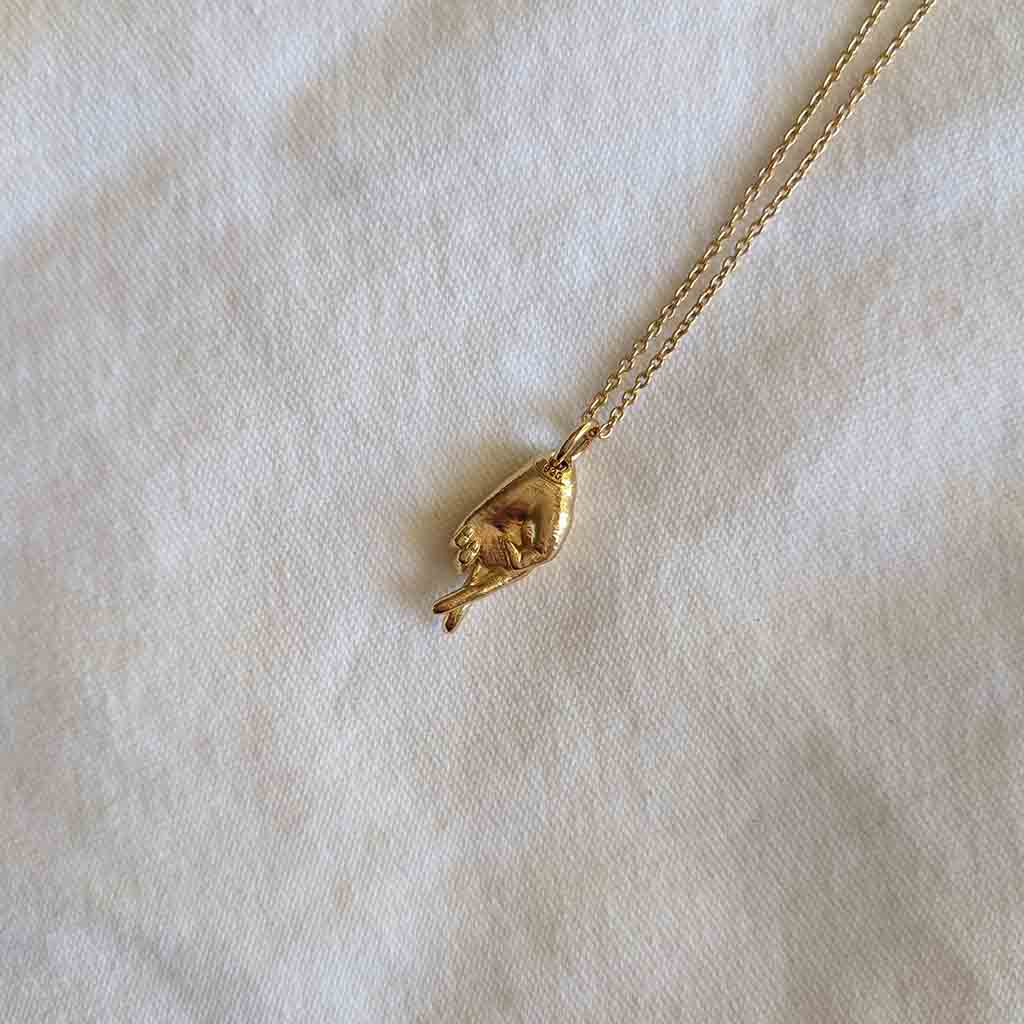 Jewelry for a capsule wardrobe. Minimalist good luck charm necklace in gold.