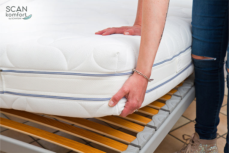 Woman putting soft mattress on bed