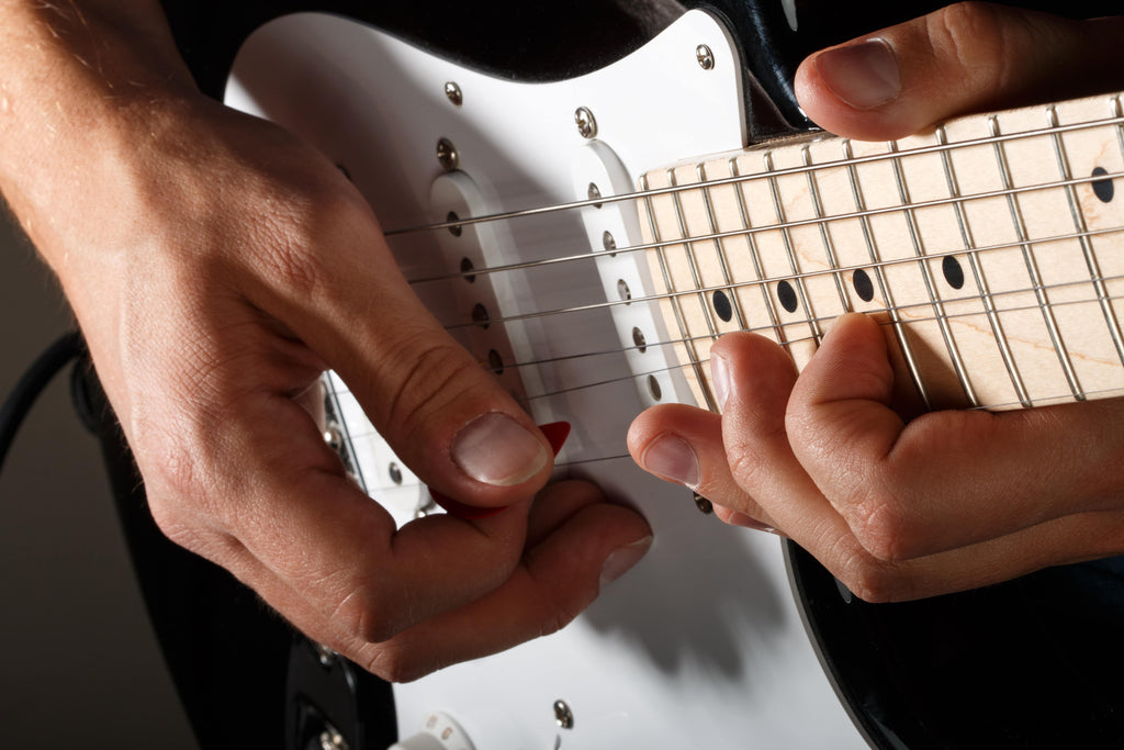 close up of fingers playing an electric guitar