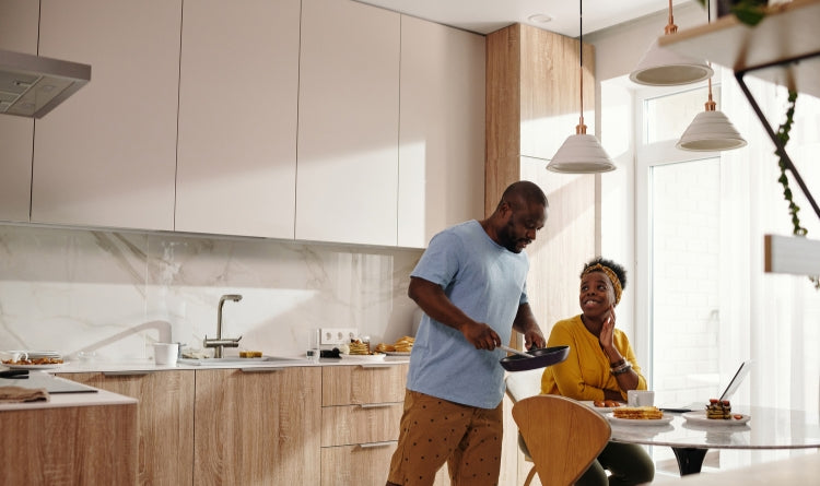 look for a range hood company that offers warranties to protect yourself image showing couple eating breakfast and looking at laptop