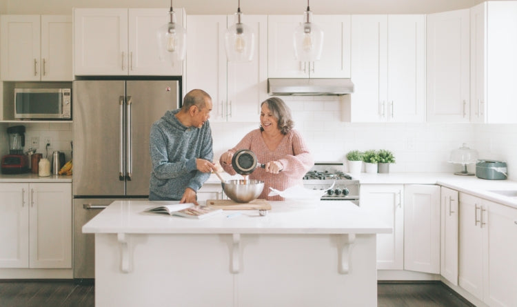 a properly functioning range hood should not leak cold air. couple cooking in the kitchen with their new good range hood