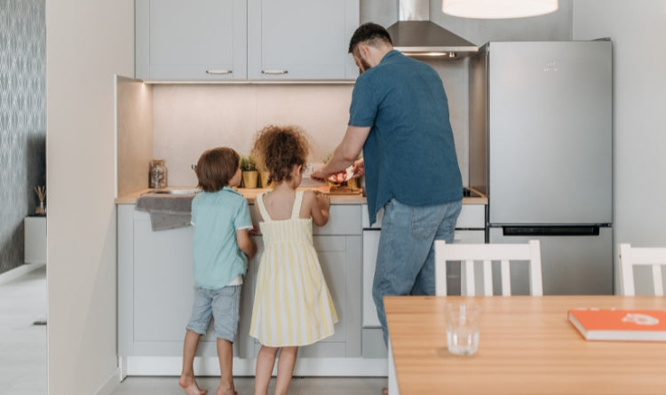 how to use your kitchenr range hood to minimize grease while cooking image showing 2 kids and a father cooking breakfast