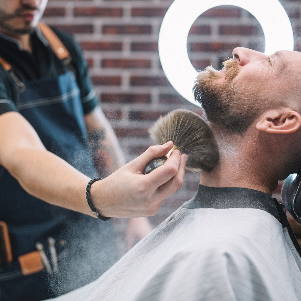 Barber brushing off man's beard neck hair