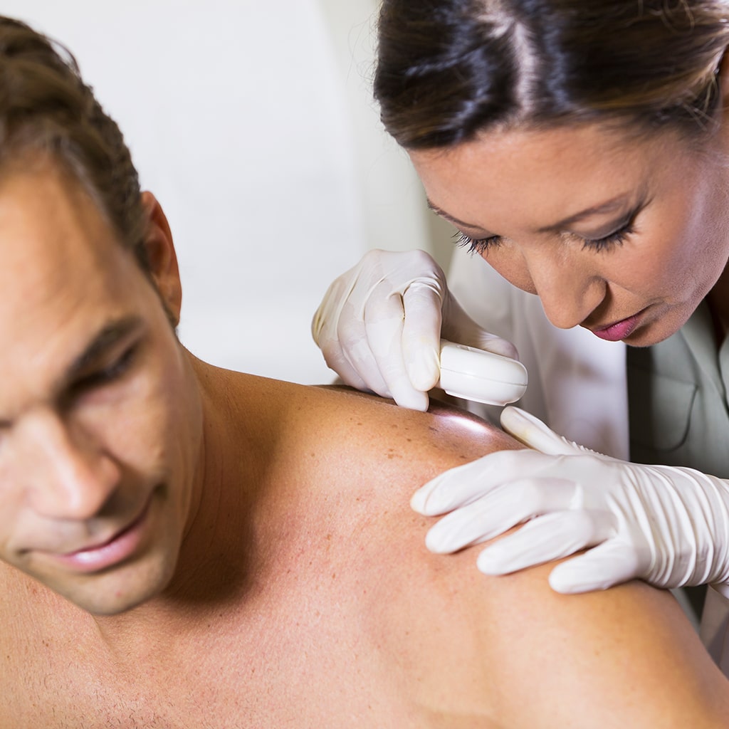 Female dermatologist examining male patient