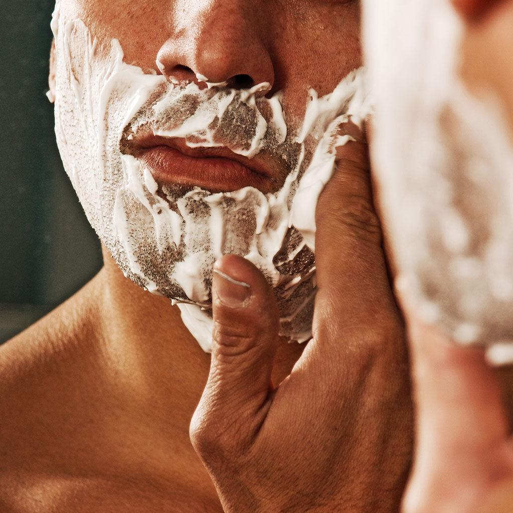 Man applying shaving cream on beard