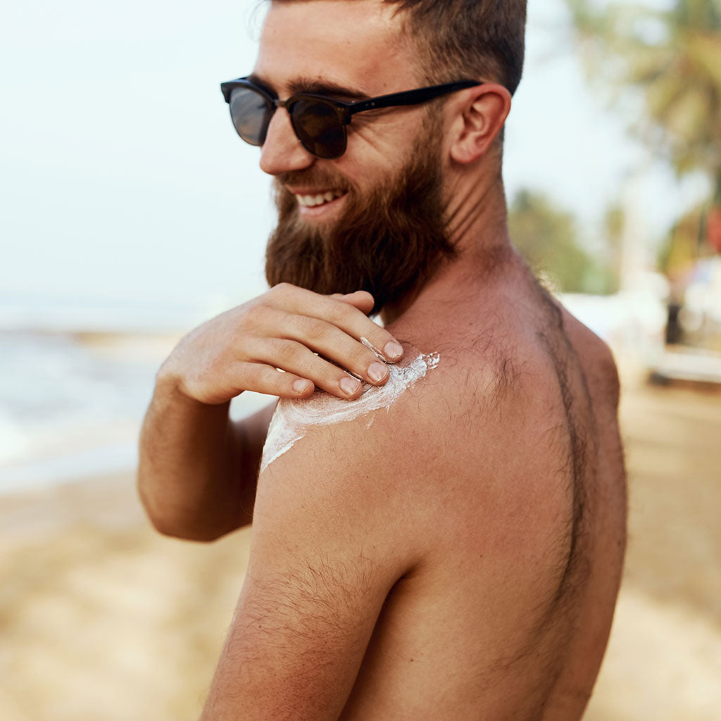 Man With Beard With Sunglasses Sunbathing With Sunscreen Lotion Body In Summer